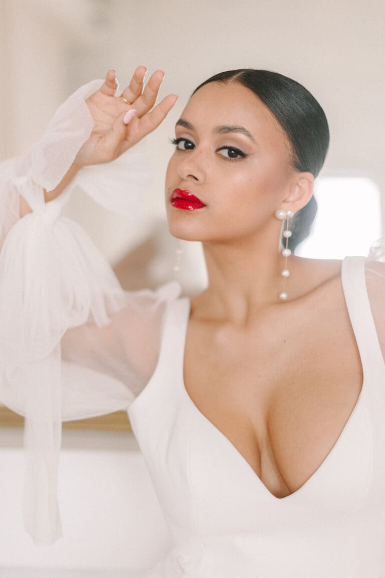 Elegant bridal makeup with bold red lipstick and pearl earrings in Montreal