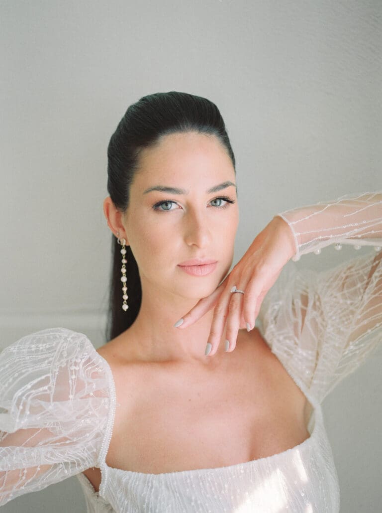 A bride with sleek hair and bold eye makeup in Montreal, wearing a modern wedding dress with puffed sleeves